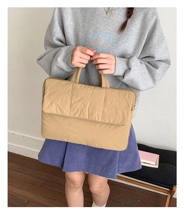 Lifestyle shot of khaki quilted laptop tote bag with zipper closure and padded handle