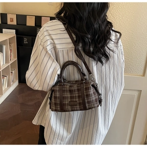 Detail of vintage brown plaid Boston bag showing texture and leather strap on a model