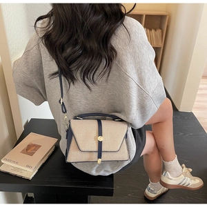 Détail du sac à main en toile beige et cuir bleu marine avec boucle en métal doré