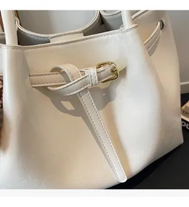 Gros plan détaillé du sac en cuir blanc crème avec boucle métallique carrée dorée polie