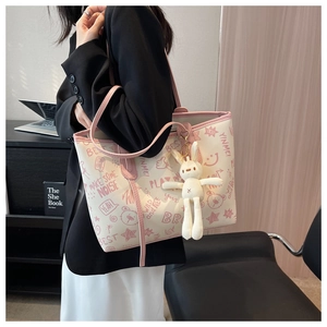 Dettaglio della borsa tote stampata con ciondolo a coniglio e manici rosa sopra un blazer nero