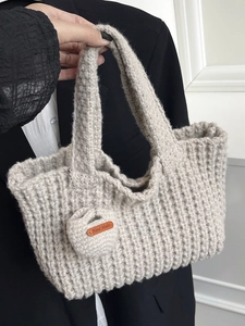 Beige chunky knit underarm bag with handmade tag and vertical textured woven design