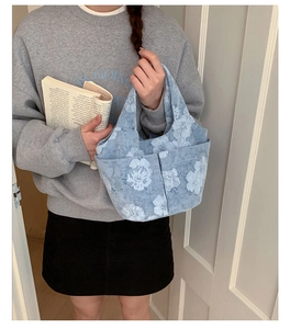Close-up of light blue floral tote bag with double front pockets and canvas texture