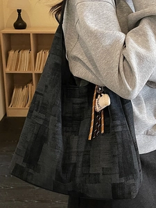 Black large-capacity dumpling bag with geometric texture and coffee plush charm decoration
