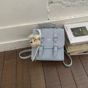 Detail of light blue PU square backpack with flip-top cover and cute plush puppy charm