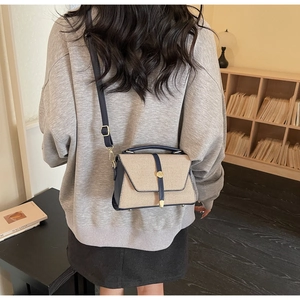 Vue détaillée du sac à bandoulière en toile beige et cuir bleu marine porté par un mannequin