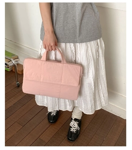 Pink quilted laptop bag held by a model in a casual setting showing the soft texture