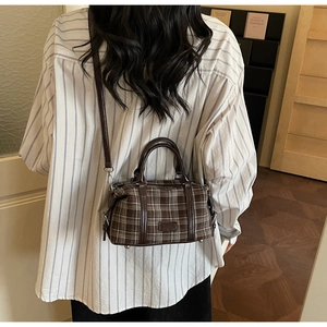 Detail of retro plaid Boston bag with brown leather handles and adjustable shoulder strap
