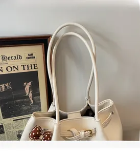 Détail du sac cabas en cuir blanc cassé avec boucle dorée et breloque à pois