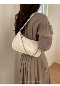 Détail du sac sous le bras en cuir blanc crème avec une fine chaîne métallique argentée