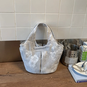 Detail of grey embroidered tote with large floral patterns and front pockets for daily commute