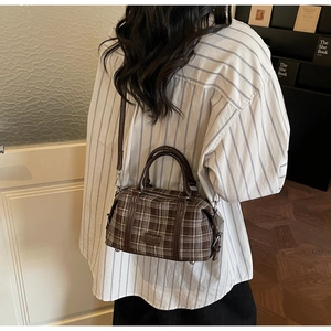 Rear view of a model wearing a brown plaid Boston bag with leather trim in a cozy room