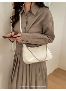 Sac demi-lune blanc crème chic avec chaîne argentée porté sur tenue grise