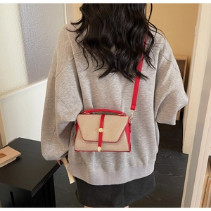 Détail du sac à main bicolore rouge et beige avec boucle ronde dorée et bandoulière chic