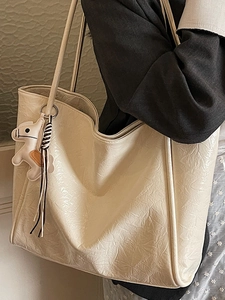 Minimalist beige tote bag with glossy wrinkled texture and small horse charm for work