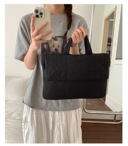 Quilted black puffer tote bag with padded texture and dual handles shown in a mirror selfie