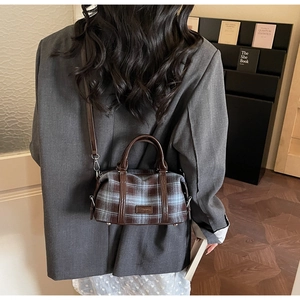 Detailed view of vintage plaid Boston bag with leather straps and metal D-ring hardware