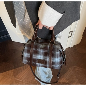 Detailed view of vintage plaid Boston bag with leather logo tag and brown handles