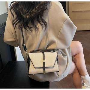 Détail du sac patchwork en toile beige et cuir noir avec un fermoir en métal doré