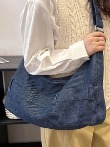 Blue striped canvas hobo bag with adjustable strap shown on model in a minimalist setting