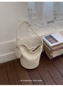 Vue détaillée du sac seau en cuir crème avec sa pochette ronde à fermeture éclair assortie
