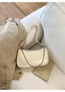 Sac bandoulière beige minimaliste avec chaîne argentée et lettrage NO FILTER sur canapé