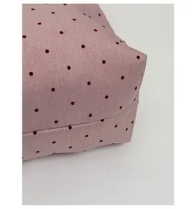 Detail of light pink tote bag featuring red polka dots and a rich woven texture