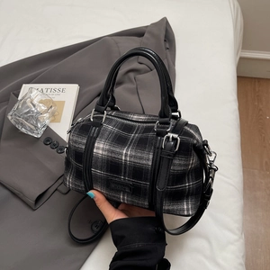 Detailed view of checkered bowling bag with leather handles and adjustable shoulder strap