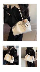 Détails d'un sac cabas en cuir blanc avec charm ours en peluche et chaîne de perles