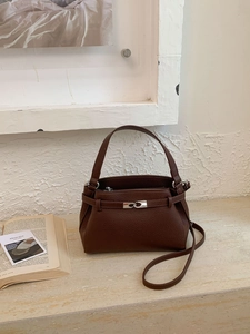 Dettaglio della borsa in pelle martellata marrone scuro con chiusura argento su marmo
