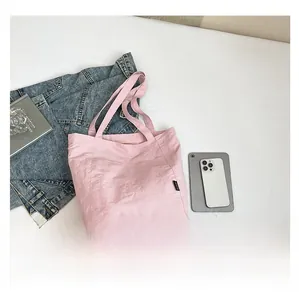 Pink minimalist tote bag shown with daily essentials like books and a phone