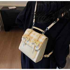 Detail view of yellow plaid backpack with bow decor and adjustable leather strap