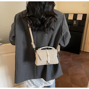 Détail du sac bandoulière en toile beige avec boucle dorée et bandoulière réglable