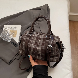Detail of vintage plaid bowling bag with brown leather trim and silver metal hardware buckle