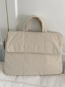 Minimalist beige quilted laptop tote bag with a sleek padded design for daily commute