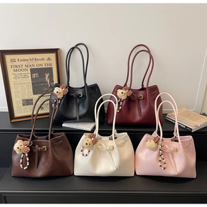 Détail de sacs fourre-tout seau en cinq couleurs avec breloques ours et cordons de serrage
