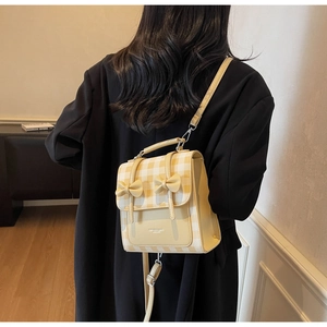 Detail shot of mini beige plaid backpack with two bows and adjustable leather straps