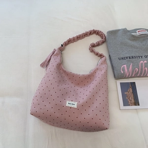 Detail of pink polka dot canvas tote with ruffle strap and lace brand label