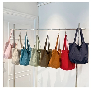 Detailed row of colorful fabric tote bags in pink, blue, and green on a rack