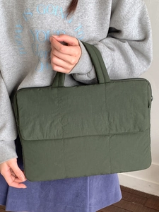 Deep green quilted laptop tote bag with a minimalist checkered pattern held by a model