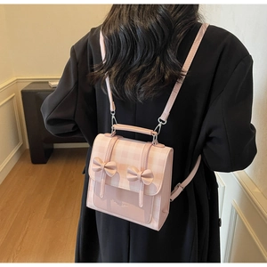 Detailed back view of a pink plaid backpack with decorative bows on a model's outfit