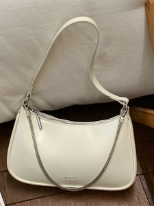 Sac à épaule beige minimaliste avec chaîne argentée et texte NO FILTER sur sol en bois