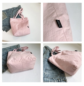 Detail of pink nylon tote bag with text label and lightweight textured fabric material
