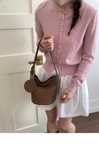 Détail d'un sac seau en cuir marron avec breloque assortie et bandoulière à nœud chic