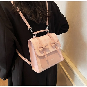 Detailed view of pink plaid backpack with bow accents worn by model to show scale