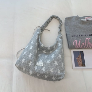 Detail of grey canvas tote bag with white stars, ruffle strap, and lace brand tag