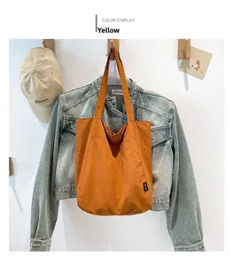 Detail view of yellow canvas tote bag with front pocket hung on a wooden hook