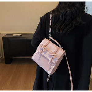 Detail of pink and white checkered backpack with decorative 3D bows and fashion lettering