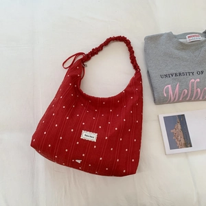 Macro detail of red floral tote bag featuring ruffled strap and wavy logo patch texture