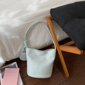Détail du sac seau bleu clair montrant la texture cuir litchi et l'anse à nœuds